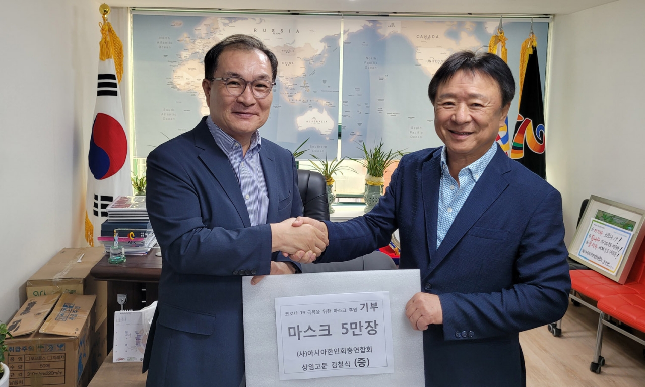 김철식 전 치앙마이한인회장(왼쪽)이 심상만 아시아총연 회장에게 마스크를 전달했다.
