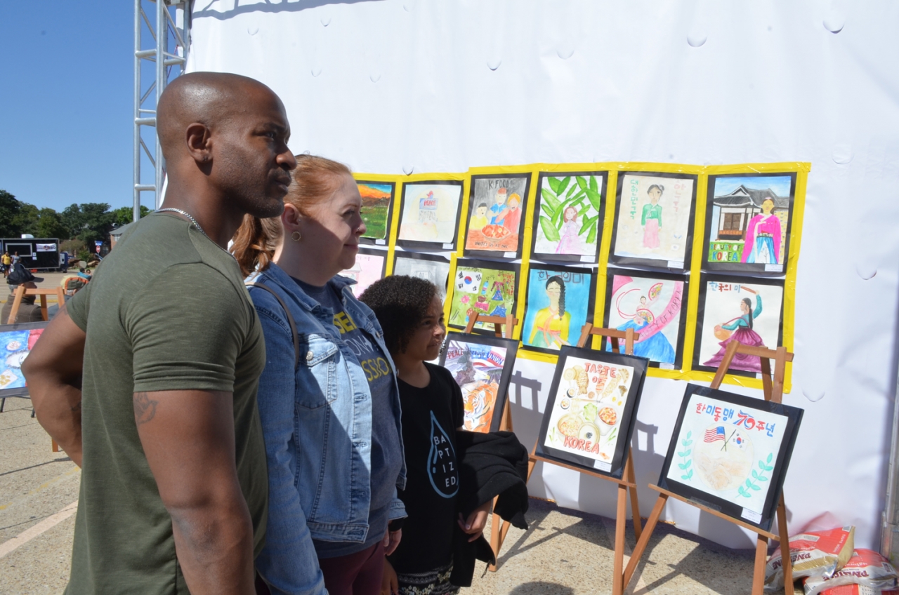 코리안 페스티벌을 찾은 미국인 가족이 민주평통 달라스협의회 주최 통일 그림 공모전 작품들을 감상하고 있다.