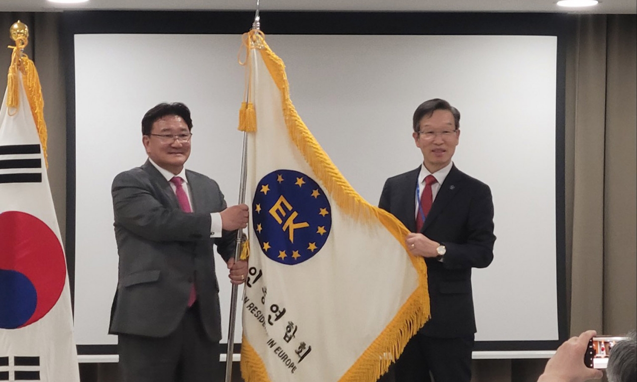유제헌 회장이 김영기 신임 유럽총연 회장(왼쪽)에게 총연 깃발을 전달했다.